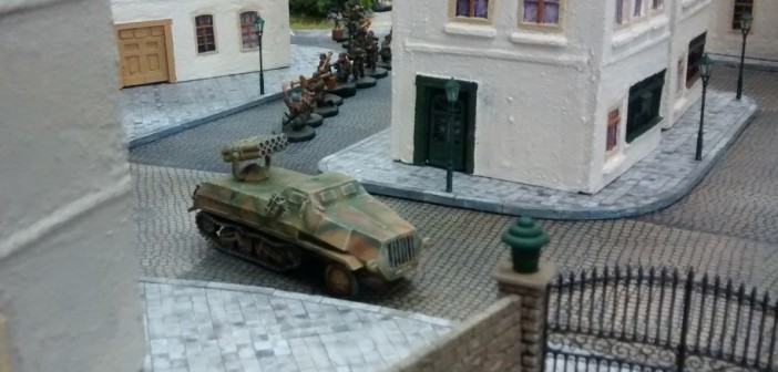 Ein Panzerwerfer 42 biegt in die Straße entlang des Rosengarten ein, gefolgt von einem 10er-Trupp Infanterie. Hier ist das erste Table-Top-Spiel bereits im Gange. Der Spieler der deutschen Seite lässt vorrücken.