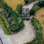 Die Wege durch die Bocage sind eng und verschlungen. Der Tiger-Panzer schafft es mit Mühe. Links im Bild weitere Reserven an Goliath-Kampfmitteln des Spielers der deutschen Seite.