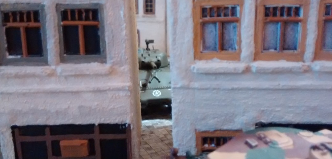 Ein Sherman kiebitzt zwischen zwei Häusern durch und will sich an der Flanke des einen Tigers versuchen.