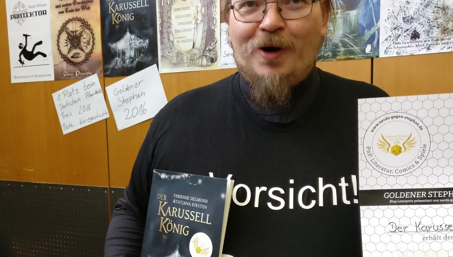 Stolz hält Torsten Low die Urkunde des Goldeneen Stephan 2016 ( Kategoeie "Roman" ) und sein Buch "Der Karusellkönig" hoch, für das er den Preis abgeräumt hat. 