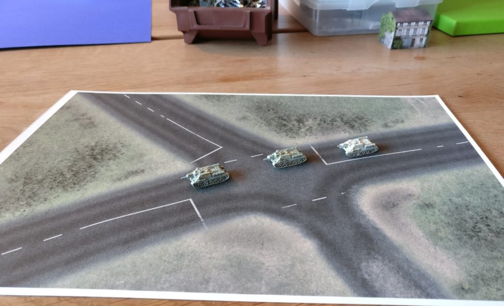 Drei SU-122 auf einer Straßenkreuzung. Die Spielplatte hat die Größe DIN A4. Maßstab 6mm / 1:285.