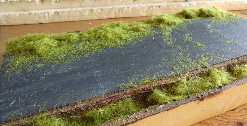 Das Gras wird in zwei Längen aufgetragen. Ganz unten im Graben kommt 6,5mm-Gras, weiter oben kürzereres 2,5mm-Gras zum Einsatz.