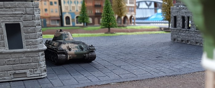 Ein T-34/76 geht hinterm Haus in Stellung.