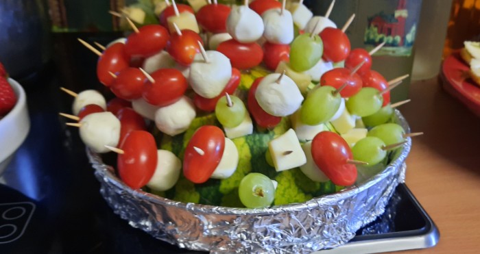 Stilecht in eine halbe Wassermelone eingesteckt: die Tomaten-Käse-Trauben-Spiesschen. Es leben die Sixties!